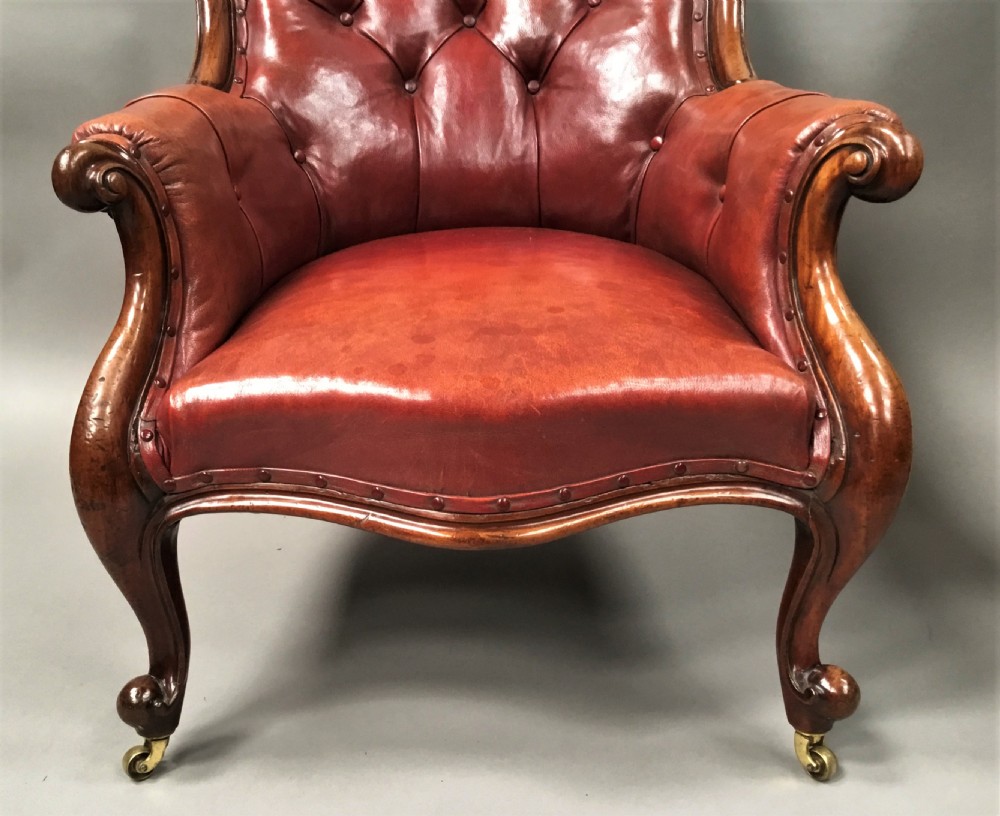 A pair of Victorian mahogany armchairs upholstered in button-backed deep red leather featuring scrolled arms and front cabriole legs on brass castors. View VI