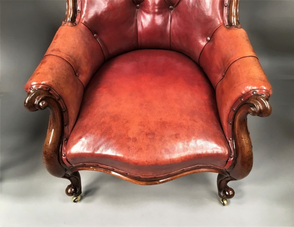 A pair of Victorian mahogany armchairs upholstered in button-backed deep red leather featuring scrolled arms and front cabriole legs on brass castors. View XI