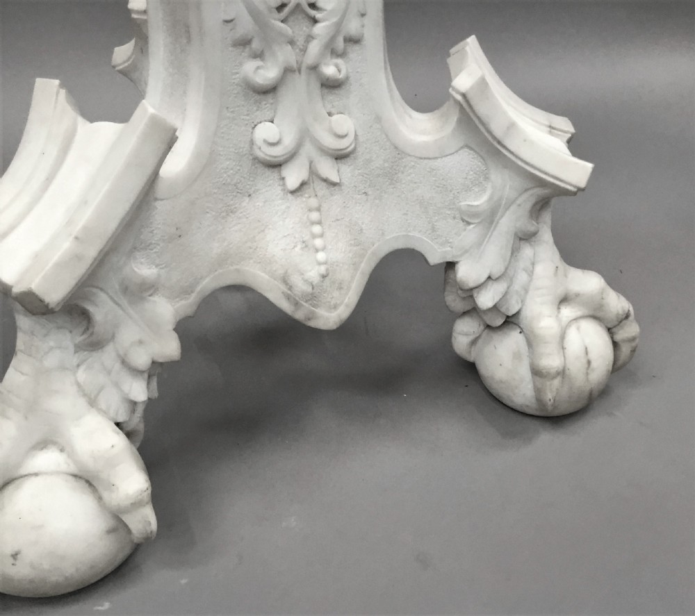 A nineteenth-century carved white Carrara marble torchere stand featuring classical maiden heads, elaborate foliate carvings, a fluted column, and claw feet. View IX