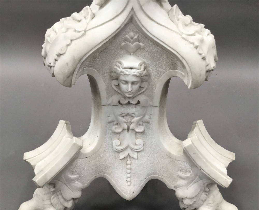 A nineteenth-century carved white Carrara marble torchere stand featuring classical maiden heads, elaborate foliate carvings, a fluted column, and claw feet. View XV