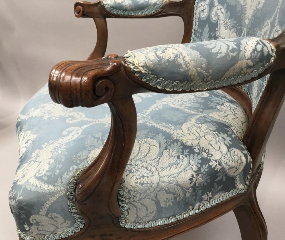 A pair of 18th-century Italian open armchairs featuring carved walnut frames, cabriole legs, and light blue damask pattern upholstery. View V