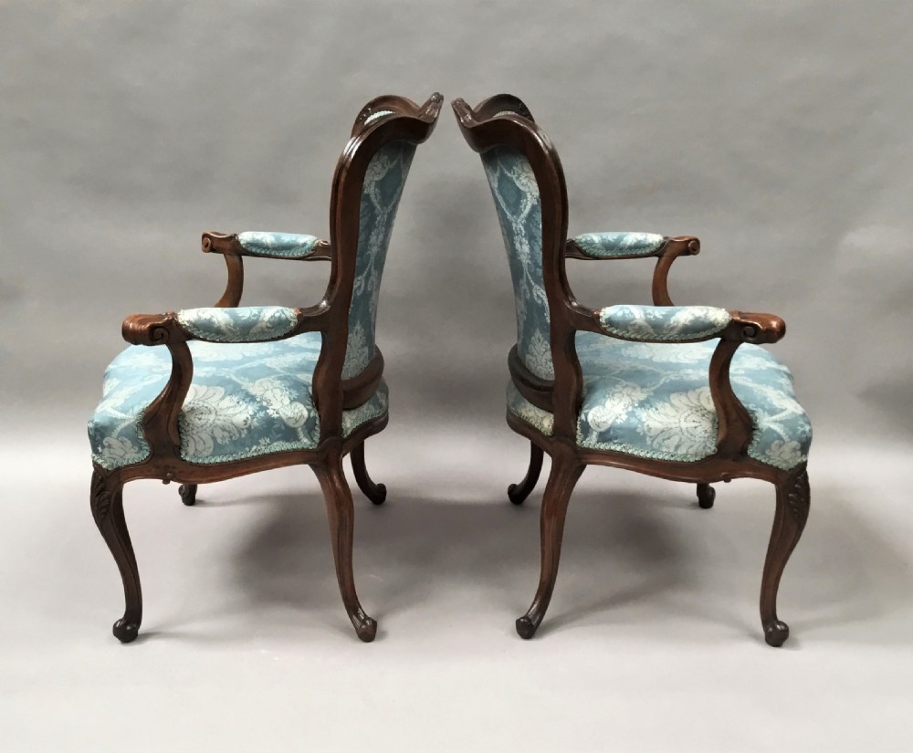 A pair of 18th-century Italian open armchairs featuring carved walnut frames, cabriole legs, and light blue damask pattern upholstery. View XV