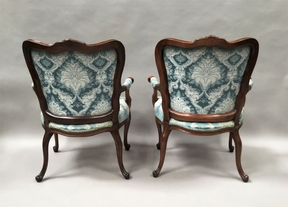 A pair of 18th-century Italian open armchairs featuring carved walnut frames, cabriole legs, and light blue damask pattern upholstery. View XVI