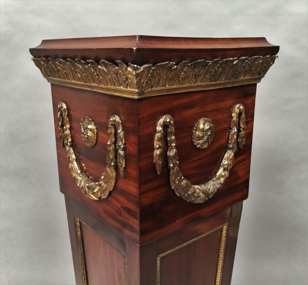 A 19th-century tapered mahogany pedestal featuring decorative gilt bronze swags, rosettes, and a moulded base. View XIII