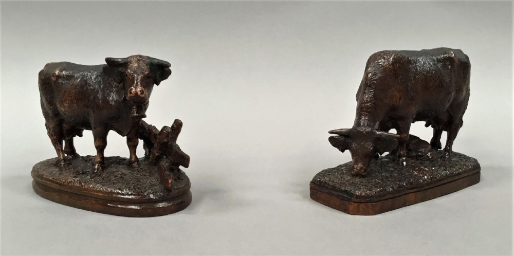 A pair of late nineteenth-century carved dark wood cows mounted on integrated plinths, showing textured coats and bells carved around their necks. View VIII