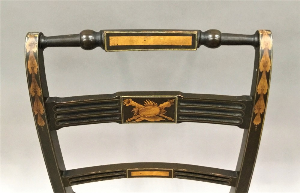 A set of six black-painted Regency side chairs featuring detailed parcel gilt decoration, horizontal slat backs, and natural woven cane seats. View III