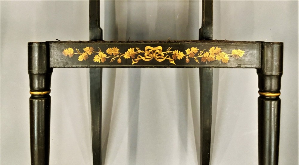 A set of six black-painted Regency side chairs featuring detailed parcel gilt decoration, horizontal slat backs, and natural woven cane seats. View IV