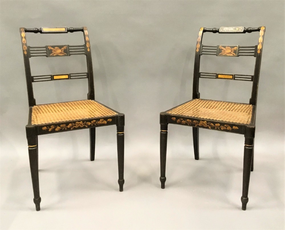 A set of six black-painted Regency side chairs featuring detailed parcel gilt decoration, horizontal slat backs, and natural woven cane seats. View VI