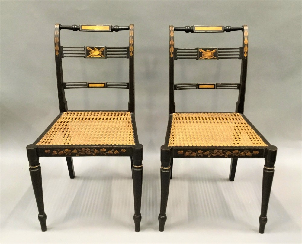 A set of six black-painted Regency side chairs featuring detailed parcel gilt decoration, horizontal slat backs, and natural woven cane seats. View VII