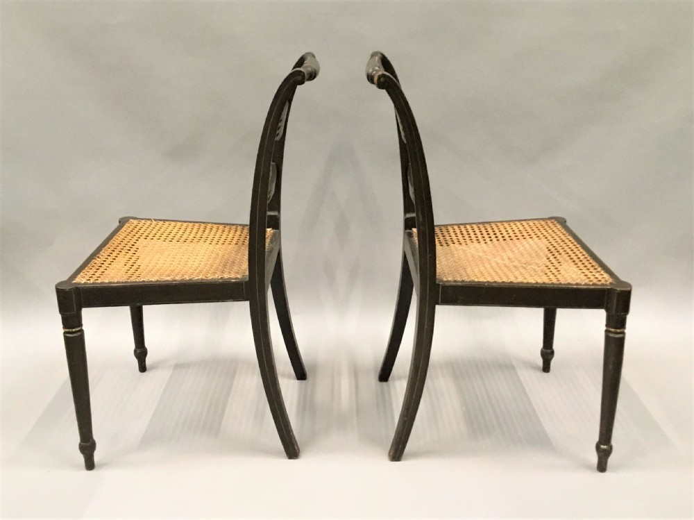 A set of six black-painted Regency side chairs featuring detailed parcel gilt decoration, horizontal slat backs, and natural woven cane seats. View VIII