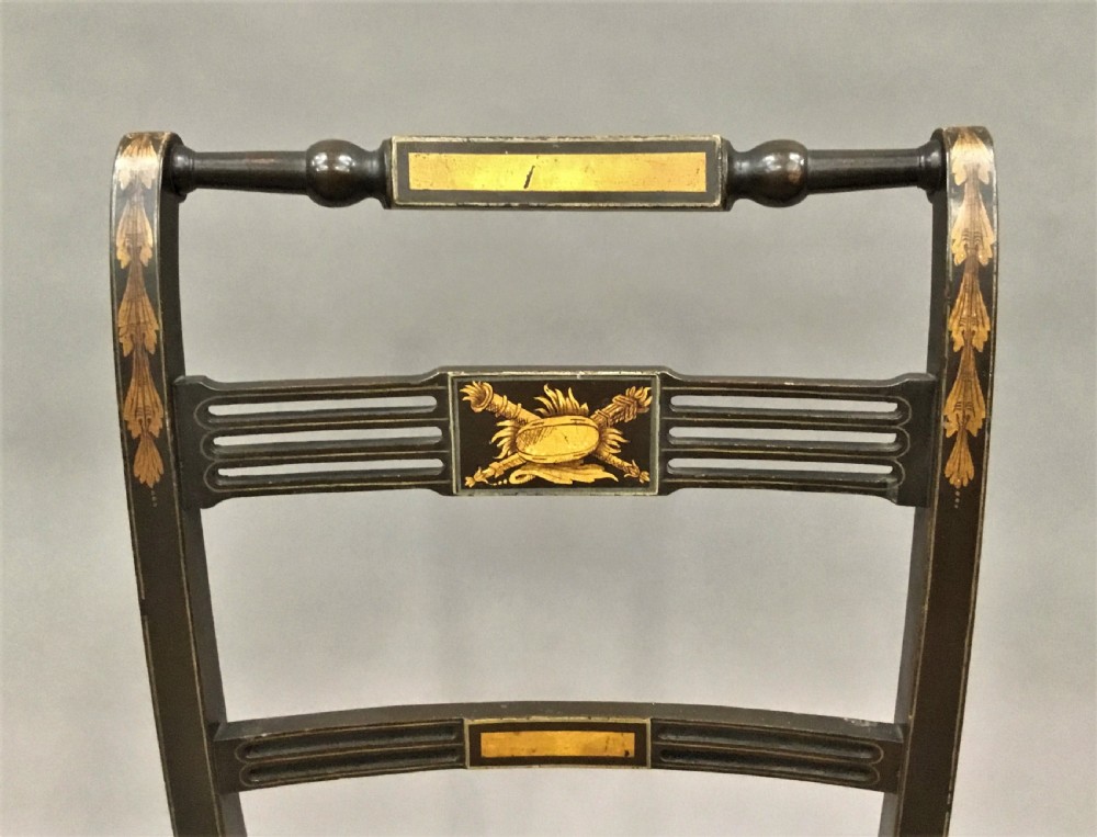 A set of six black-painted Regency side chairs featuring detailed parcel gilt decoration, horizontal slat backs, and natural woven cane seats. View IX
