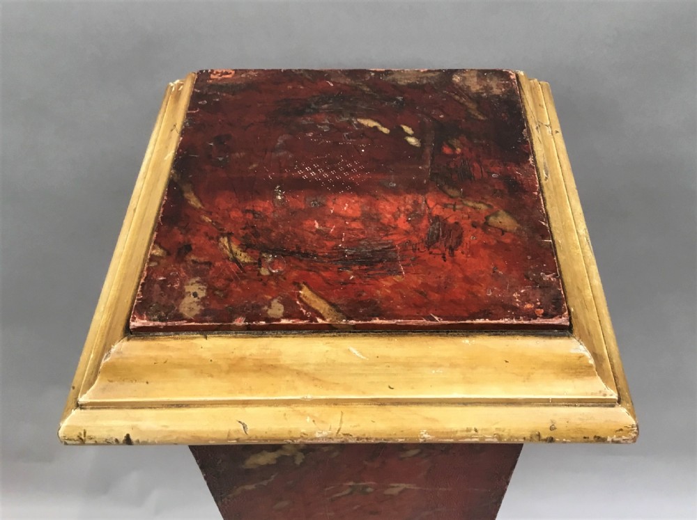 A tall tapering wooden display pedestal with a red faux-marble painted finish and gilded stepped mouldings at the top and base. View X
