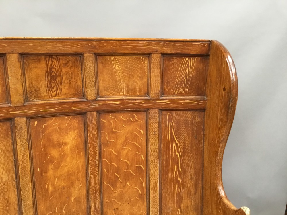 An antique Georgian high-backed wooden settle featuring a curved panelled back with a warm brown scumbled painted finish and integrated seat. View XIII