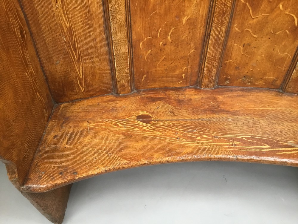 An antique Georgian high-backed wooden settle featuring a curved panelled back with a warm brown scumbled painted finish and integrated seat. View XV