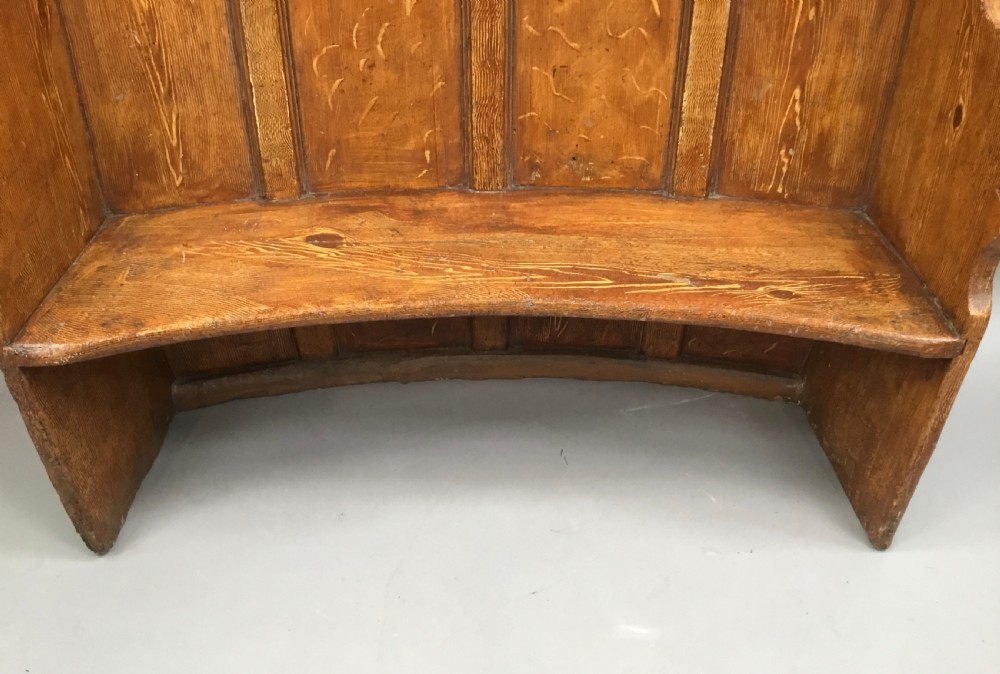 An antique Georgian high-backed wooden settle featuring a curved panelled back with a warm brown scumbled painted finish and integrated seat. View XVI
