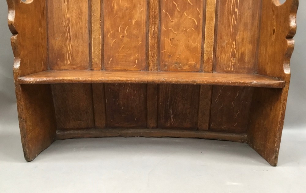 An antique Georgian high-backed wooden settle featuring a curved panelled back with a warm brown scumbled painted finish and integrated seat. View XVII