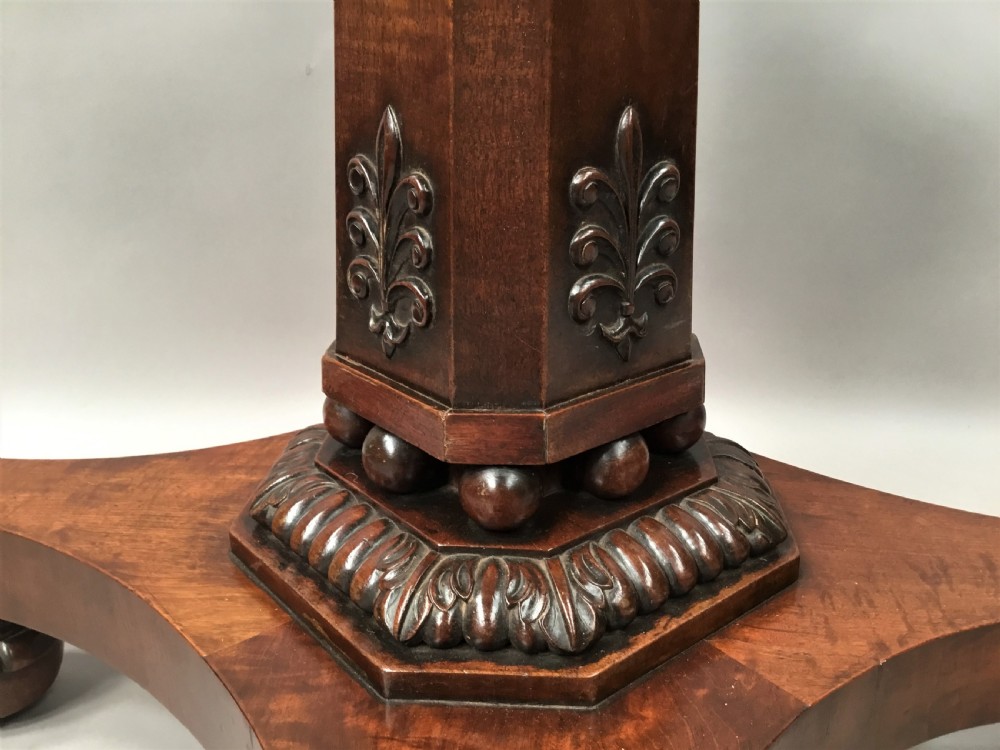 A Regency mahogany centre table featuring a rounded square top with rope-twist carved moulding, supported by a central tapered pedestal and a quadform base with lobed feet. View III