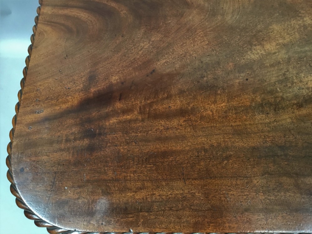 A Regency mahogany centre table featuring a rounded square top with rope-twist carved moulding, supported by a central tapered pedestal and a quadform base with lobed feet. View VIII