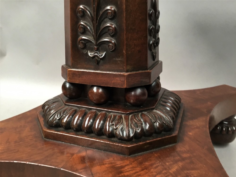 A Regency mahogany centre table featuring a rounded square top with rope-twist carved moulding, supported by a central tapered pedestal and a quadform base with lobed feet. View XI