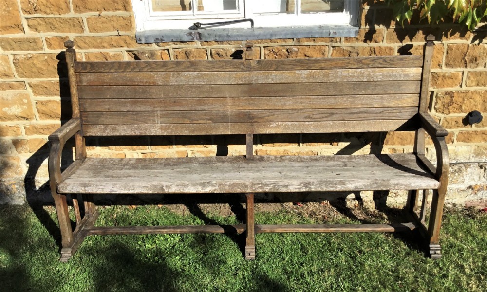 A 19th-century weathered oak orangery bench featuring a slatted back, carved finials, and Gothic-inspired side supports. View III