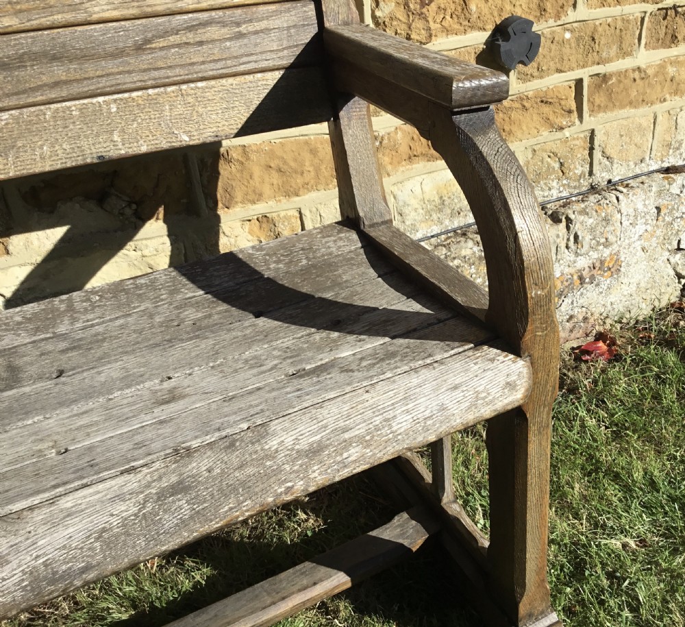 A 19th-century weathered oak orangery bench featuring a slatted back, carved finials, and Gothic-inspired side supports. View X