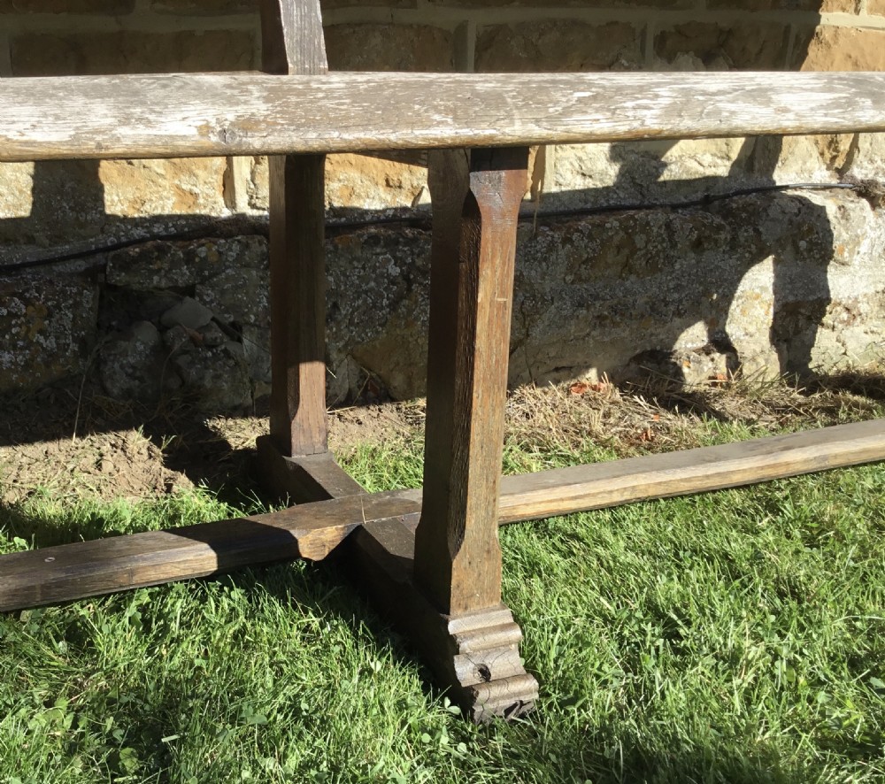 A 19th-century weathered oak orangery bench featuring a slatted back, carved finials, and Gothic-inspired side supports. View XII
