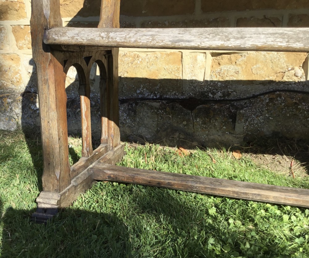A 19th-century weathered oak orangery bench featuring a slatted back, carved finials, and Gothic-inspired side supports. View XIII