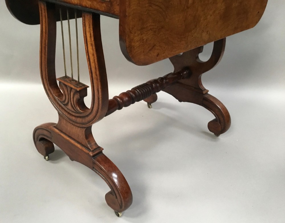 A Regency burr oak drop-flap occasional table featuring lyre-shaped side supports, a single drawer, turned stretcher, and brass castors. View X