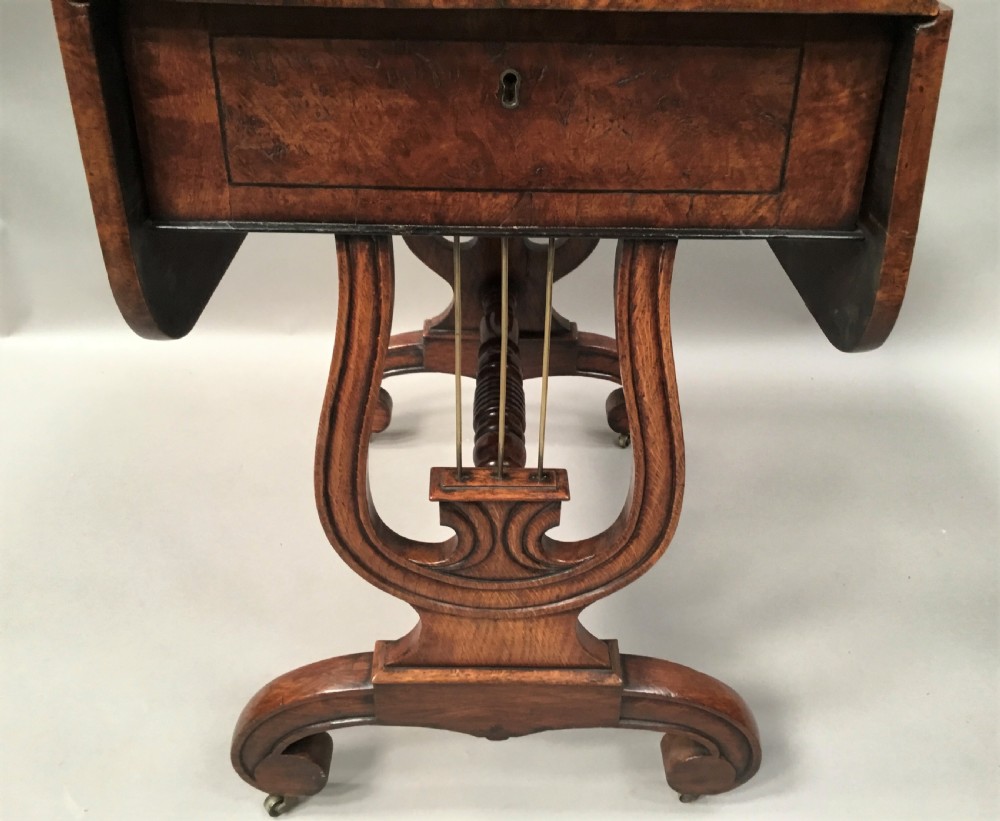 A Regency burr oak drop-flap occasional table featuring lyre-shaped side supports, a single drawer, turned stretcher, and brass castors. View XII