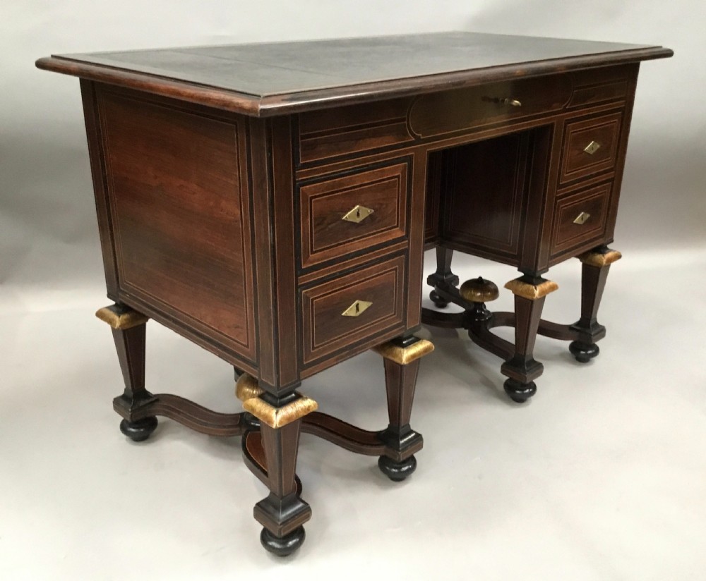 A 19th-century French rosewood kneehole desk featuring line inlay, brass escutcheons, a central recessed cupboard, and eight tapered legs connected by curved stretchers. View II