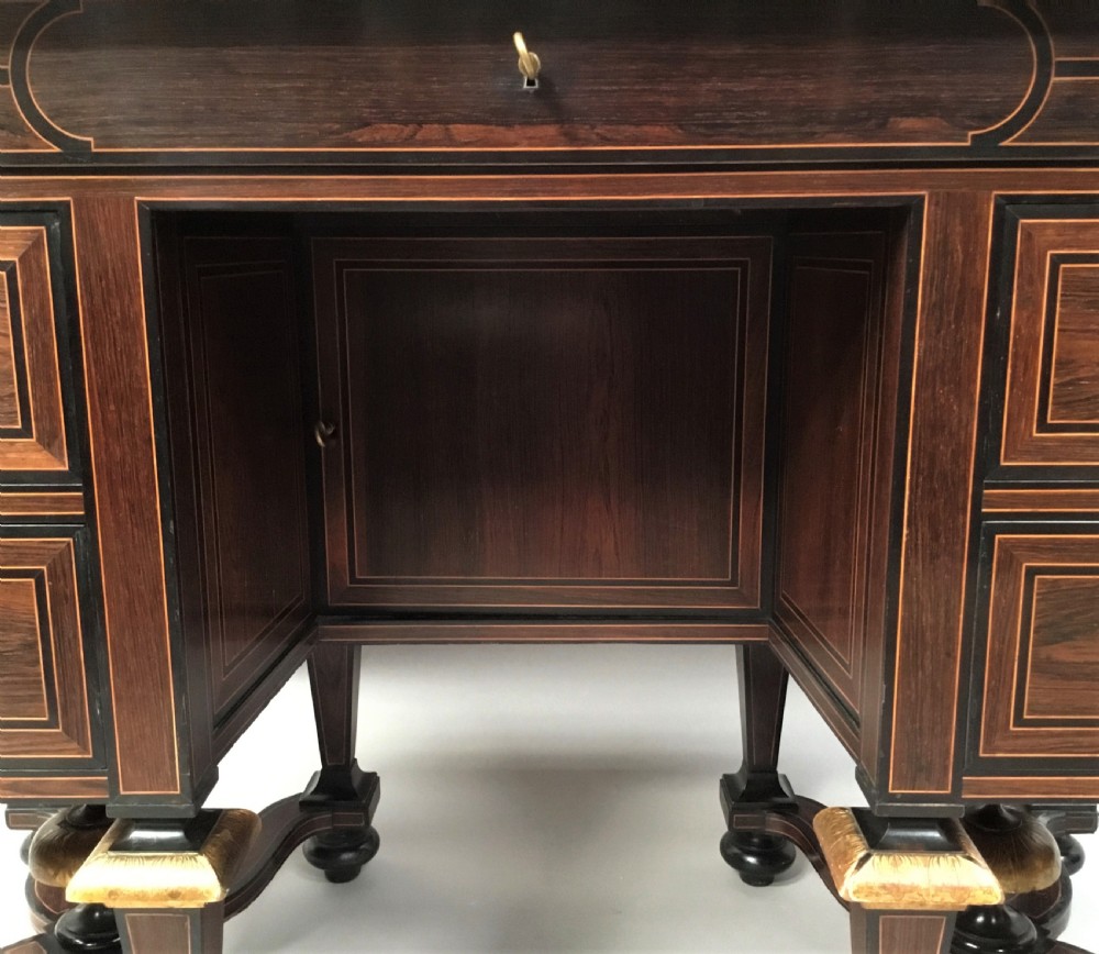 A 19th-century French rosewood kneehole desk featuring line inlay, brass escutcheons, a central recessed cupboard, and eight tapered legs connected by curved stretchers. View V
