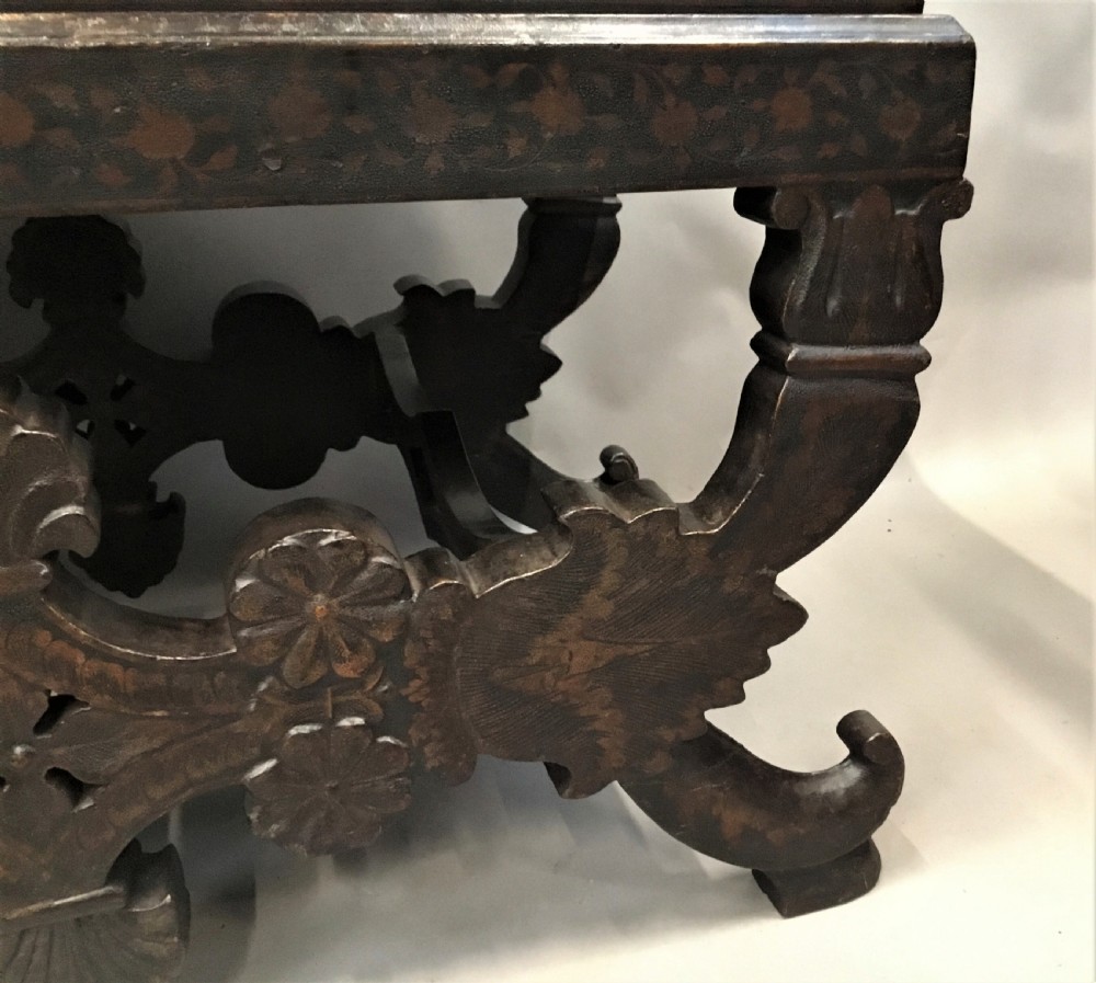A dark brown rectangular lacquered wooden chest decorated with all-over floral pattern, set on a deeply carved scrolled wooden stand. View VIII