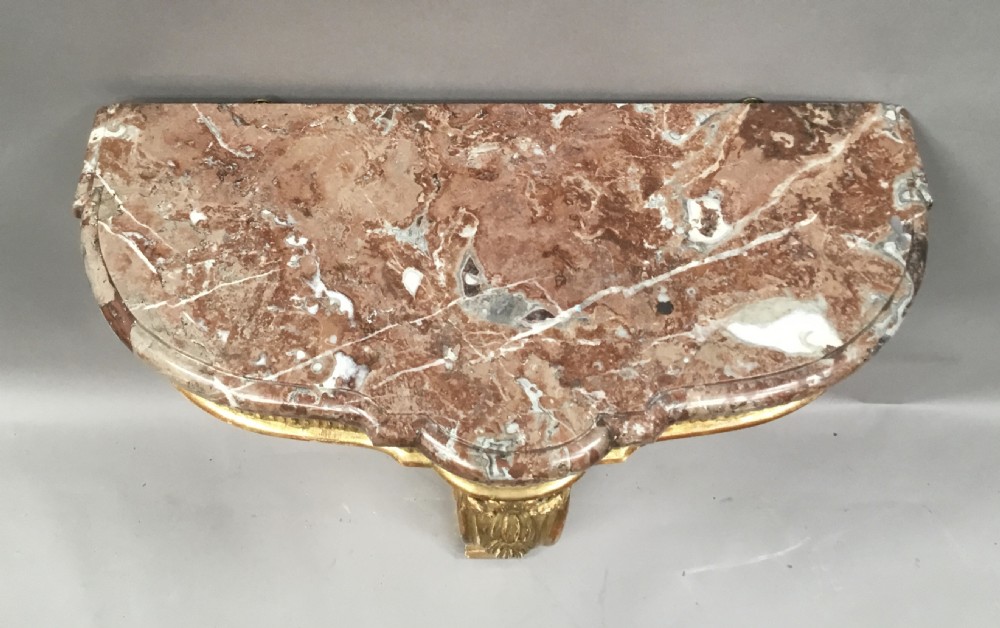 A 19th-century French Louis XV style wall-mounted giltwood console table featuring a carved single scroll leg and a shaped pink marble top. View III