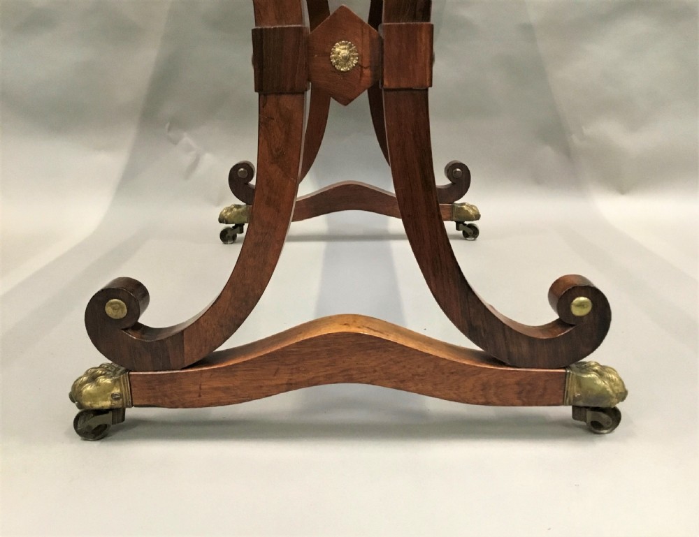 A Regency rosewood centre table featuring a rectangular brass-rimmed top supported by curved double-scroll legs with a turned stretcher and brass paw feet. View VIII
