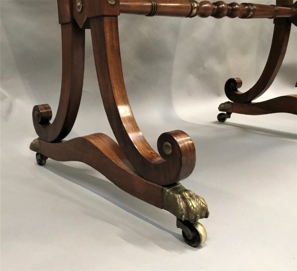 A Regency rosewood centre table featuring a rectangular brass-rimmed top supported by curved double-scroll legs with a turned stretcher and brass paw feet. View IX