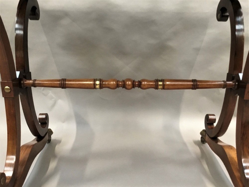 A Regency rosewood centre table featuring a rectangular brass-rimmed top supported by curved double-scroll legs with a turned stretcher and brass paw feet. View XV