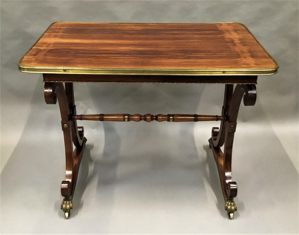A Regency rosewood centre table featuring a rectangular brass-rimmed top supported by curved double-scroll legs with a turned stretcher and brass paw feet. View XVI