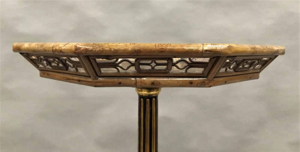A tall Regency period octagonal torchere stand featuring a black and gold lacquered tray top, reeded column, and tripod base. View IX