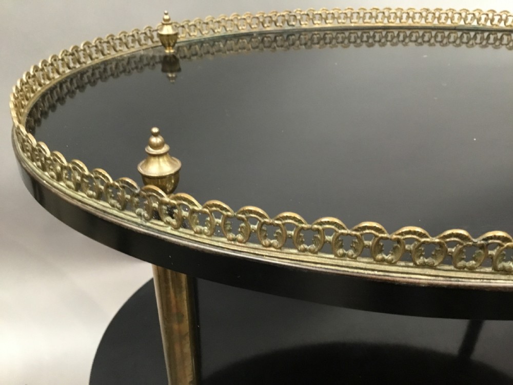 An early 20th-century oval ebonised etagere featuring two tiers, a pierced gilt brass top gallery, brass upright columns, and brass castors. View III
