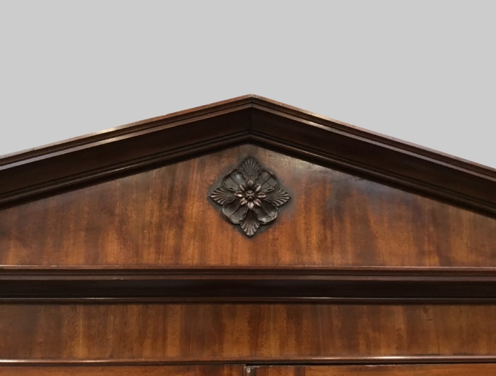 A large George III mahogany breakfront bookcase with a central pediment, glazed upper doors with geometric glazing bars, and flame mahogany cupboard doors below. View VIII