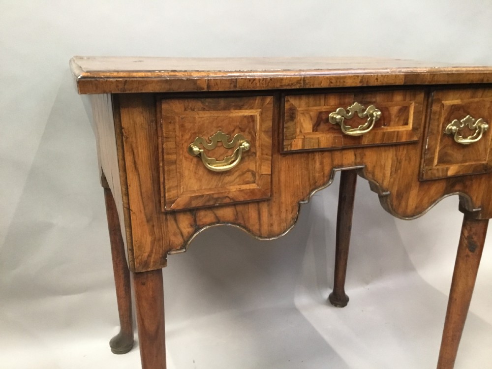 An 18th-century George I figured walnut lowboy with three drawers, brass handles, a shaped apron, and slender cabriole legs with pad feet. View IV