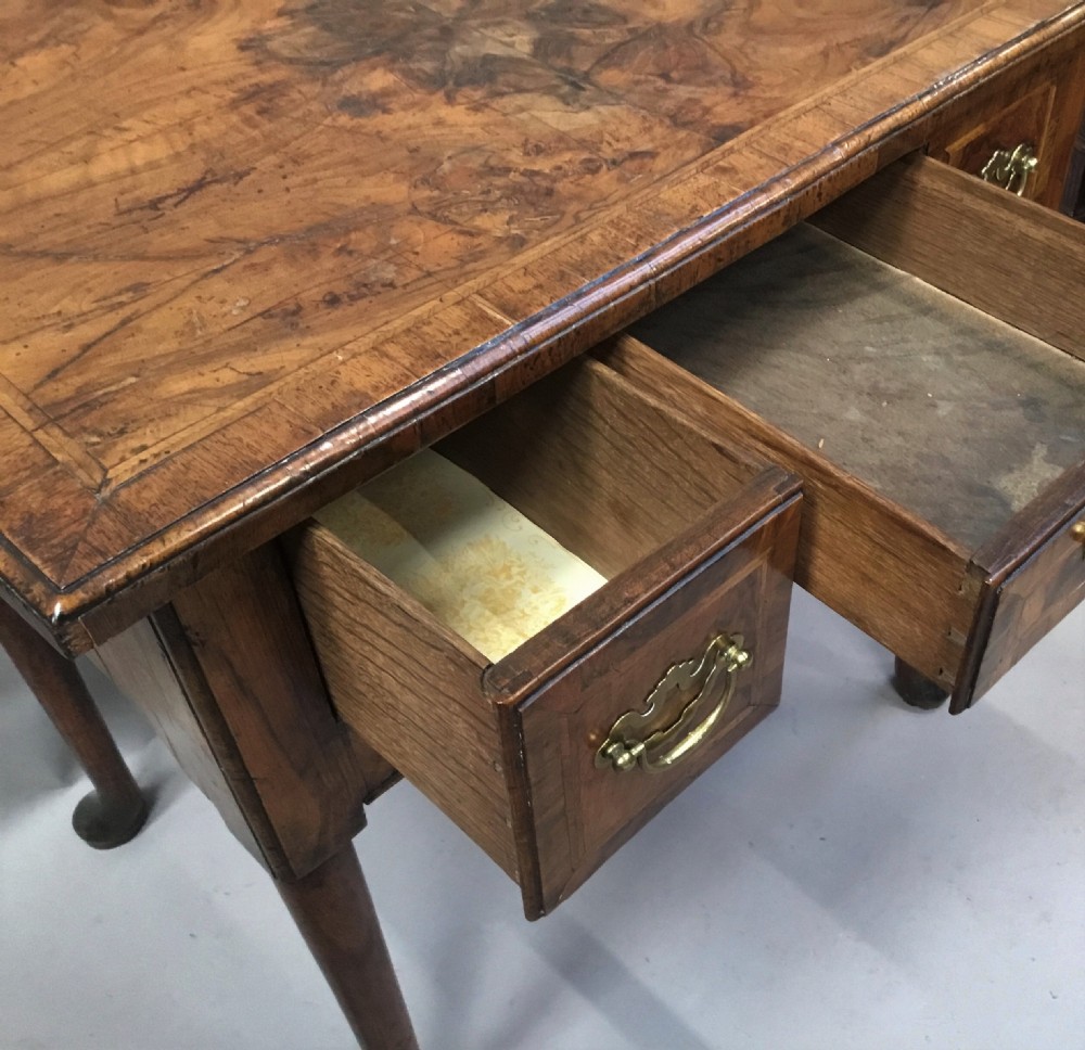 An 18th-century George I figured walnut lowboy with three drawers, brass handles, a shaped apron, and slender cabriole legs with pad feet. View IX