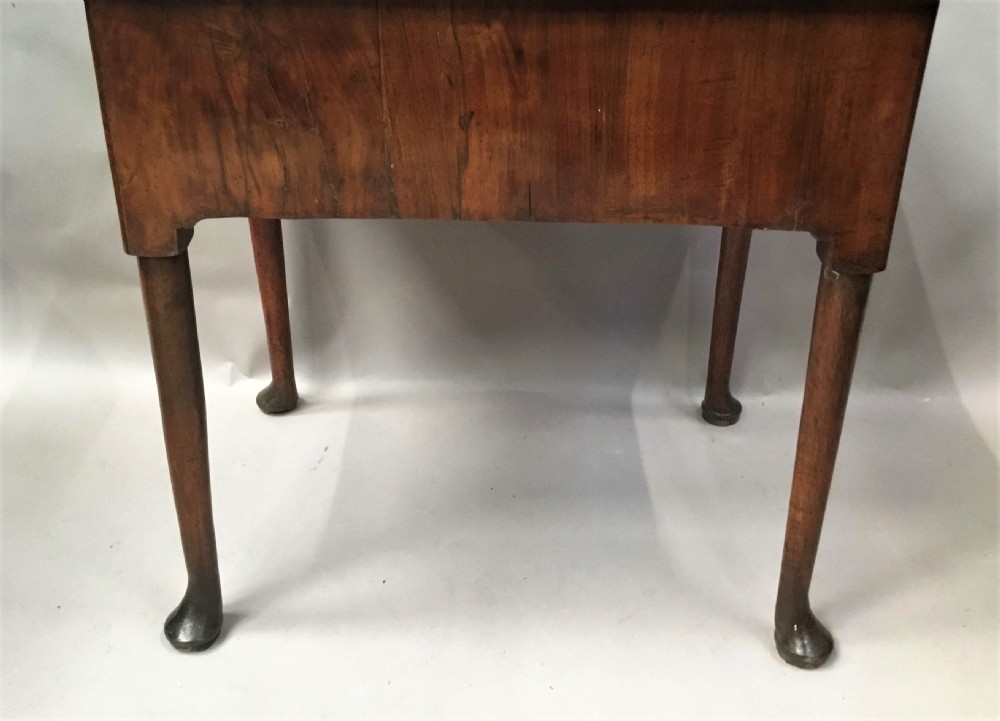An 18th-century George I figured walnut lowboy with three drawers, brass handles, a shaped apron, and slender cabriole legs with pad feet. View X
