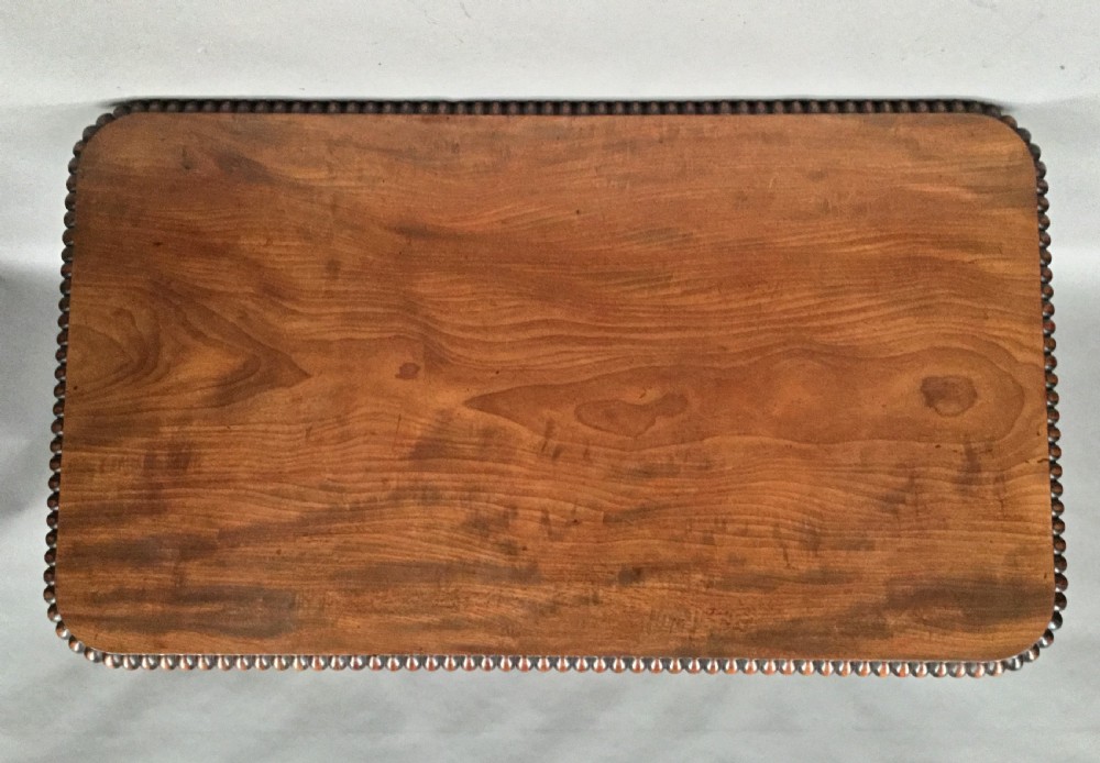 A Regency mahogany library table featuring a carved gadrooned border, reeded turned legs, and a trestle base with feet. View II