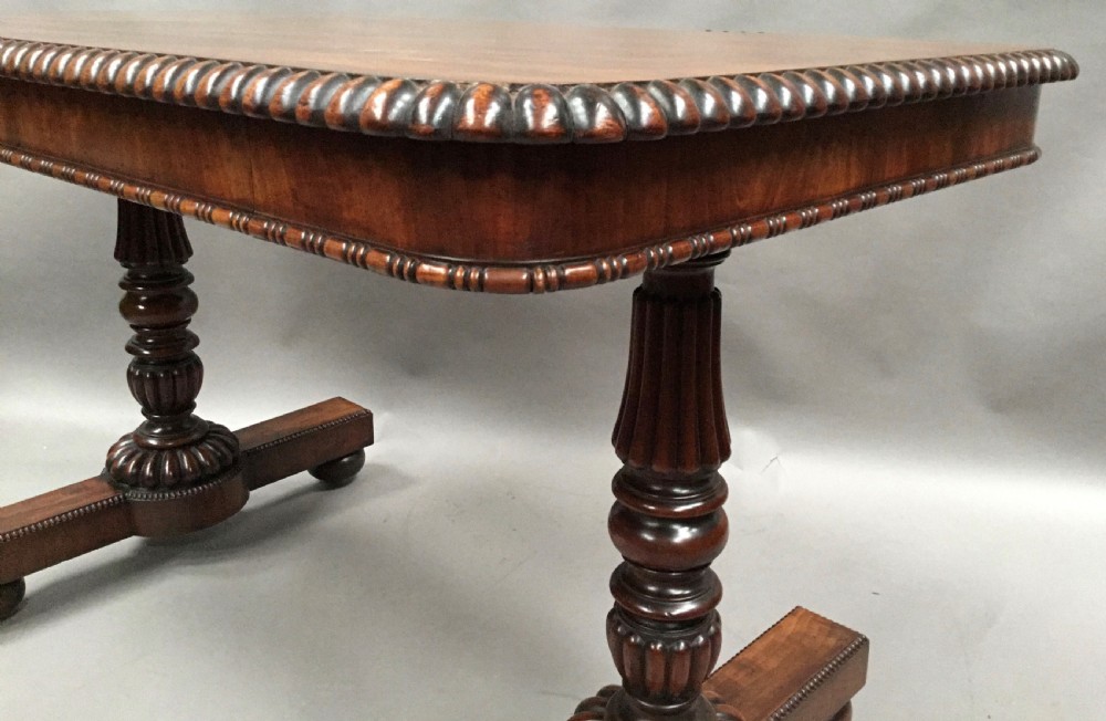 A Regency mahogany library table featuring a carved gadrooned border, reeded turned legs, and a trestle base with feet. View VI