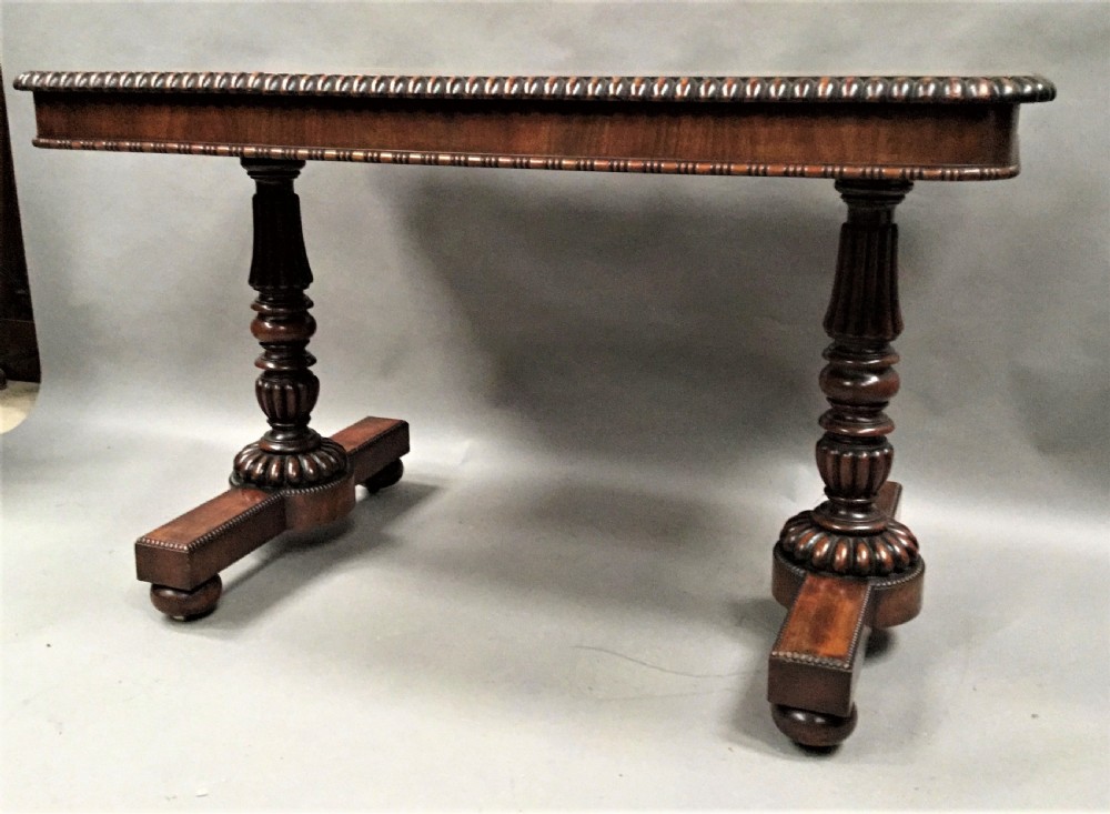 A Regency mahogany library table featuring a carved gadrooned border, reeded turned legs, and a trestle base with feet. View XI