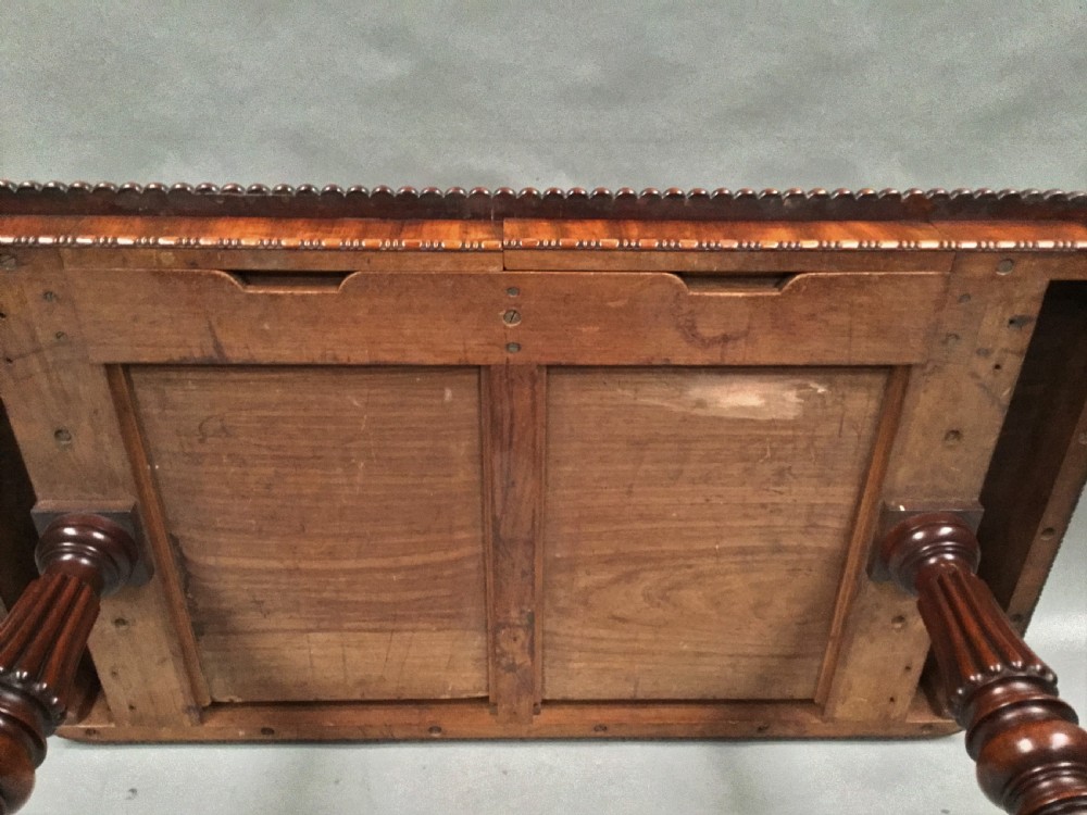 A Regency mahogany library table featuring a carved gadrooned border, reeded turned legs, and a trestle base with feet. View XII