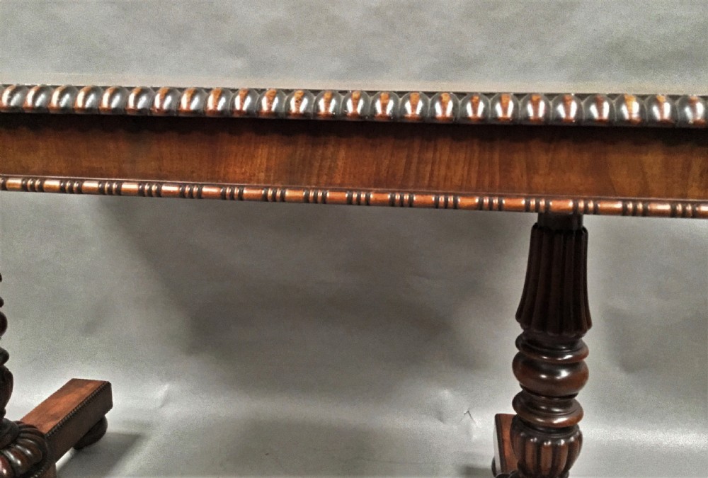 A Regency mahogany library table featuring a carved gadrooned border, reeded turned legs, and a trestle base with feet. View XVIII