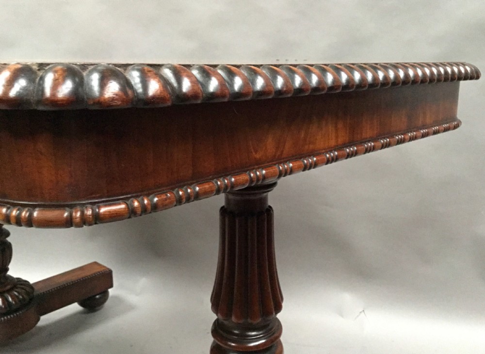 A Regency mahogany library table featuring a carved gadrooned border, reeded turned legs, and a trestle base with feet. View XX