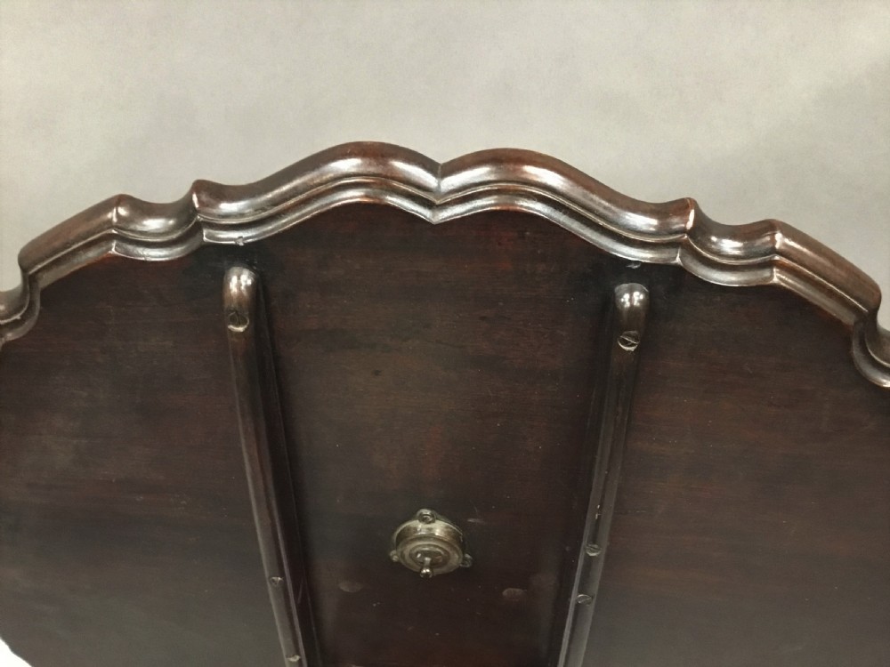 A mahogany George III style tripod table featuring a scalloped piecrust top, turned pedestal column, and cabriole legs with carved feet. View VII